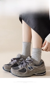 Dettaglio di sneakers retrò in mesh grigio indossate con calze in maglia con volant