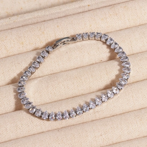 Detail of silver tennis bracelet with teardrop zircon stones on beige fabric