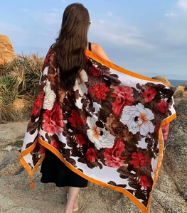 Macro shot of lightweight beach shawl with red floral print and orange borders