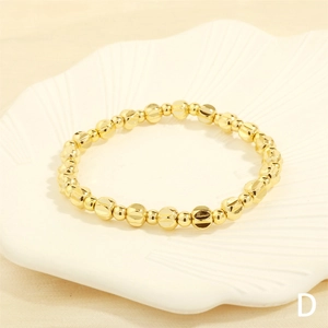Detail of gold beaded bracelet with diamond-cut facets in a white shell display tray