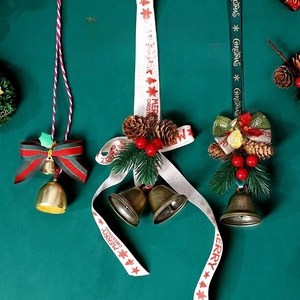 Detailed view of Christmas bow hanging ornaments with bells, pine cones and red berries