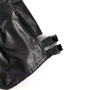 Dettaglio ravvicinato di pantaloncini in ecopelle nera con fibbie regolabili in metallo