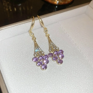 Macro shot of French violet flower earrings with purple crystals and gold hooks in a box