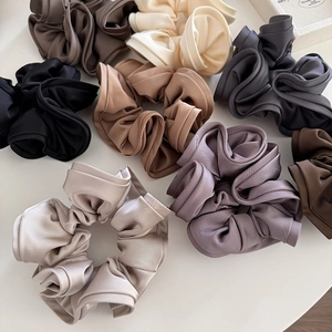 Macro shot of assorted satin silk scrunchies in neutral earth tones on white background