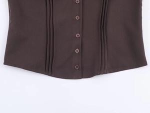Detailed view of puff sleeve top with five-button placket and vertical pleat texture