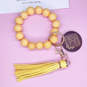 Détail du porte-clés perlé léopard jaune avec pompon en PU et breloque MAMA en bois