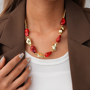 Macro detail of red acrylic droplets and irregular gold beads on a retro style necklace