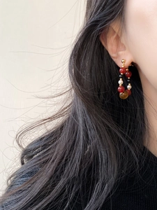 Close-up of pearl and agate beaded hoop earrings on a model with vintage ethnic style