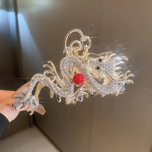 Close-up of a silver dragon hair claw clip with rhinestones and a red bead detail