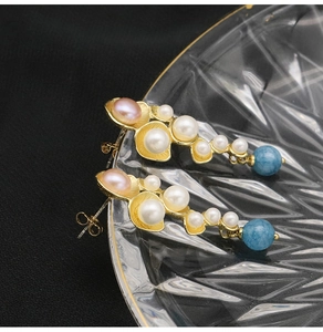 Detailed shot of leaf earrings with white and purple pearls and blue stone drops