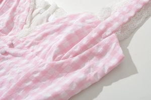 Detail of pink and white plaid dress showing V-neck lace trim and decorative buttons