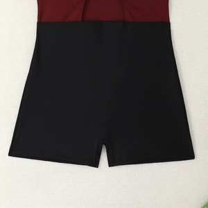 Flat lay of burgundy and black color block boy-short swimsuit with cutout details