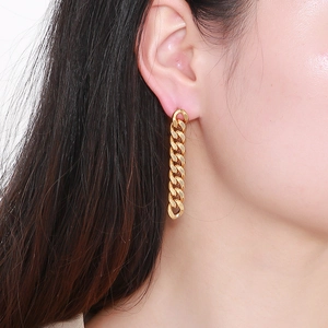 Close-up of a model wearing a long gold Cuban link chain earring with a polished finish