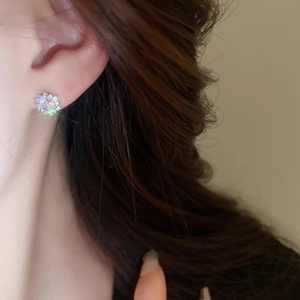 Close-up of minimalist silver snowflake stud earrings with sparkling cubic zirconia
