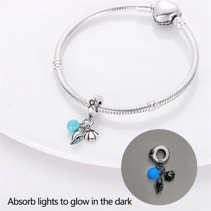 Luminous silver bracelet detail with glowing shell and conch charms on white background