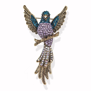 Vintage eagle brooch in gold metal with colorful purple and blue rhinestones on white background