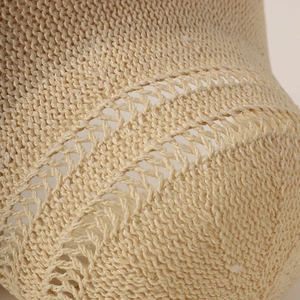 Macro shot of the beige knitted wide-brim sun hat showing detailed hollow-out texture