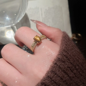 Close-up of gold plated tiger eye ring with pave zircons worn on hand in a cozy setting