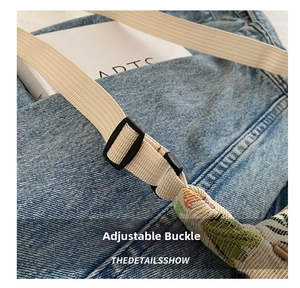Detail of adjustable beige woven strap with black plastic buckle on denim shoulder bag
