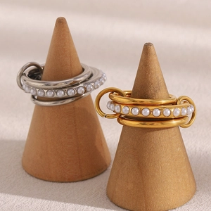 Detail of 18K gold and silver layered rings with pearls on wooden display cones