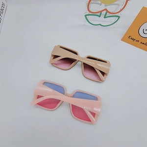 Detail view of square sunglasses in light coffee and pale pink frames with gradient lenses