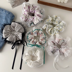 Set of six floral and lace scrunchies with ribbons and pearls on a clean desktop