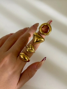 Detailed close-up of chunky gold geometric rings with a polished mirror finish on a model