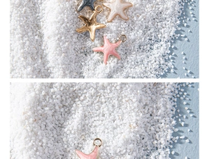 Macro detail of colorful starfish charms in pink, white and gray on white sand beach