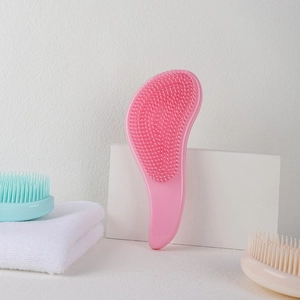 Pink and blue curved detangling brushes on white marble and towels for daily hair care