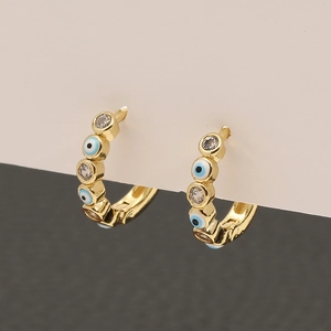 Detalle de pendientes de ojo turco dorado con esmalte azul y circonitas blancas brillantes