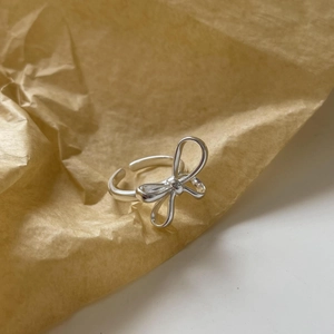 Detailed close-up of a silver bow knot ring on vintage kraft paper background