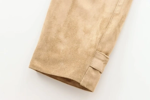 Detailed close-up of beige faux suede sleeve cuff with decorative metal buckle and stitching
