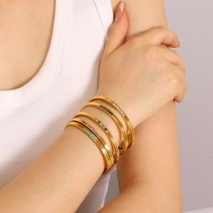 Set of four 18K gold plated stainless steel bangles with colorful rhinestones on wrist