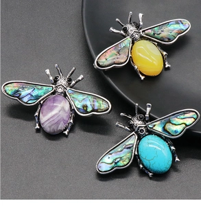 Detailed view of bee brooches with abalone shell wings and colorful agate gemstone bodies