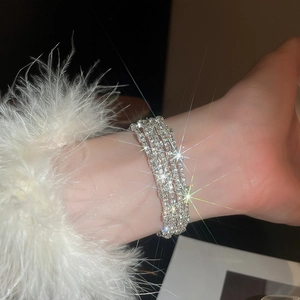 Dettaglio macro del bracciale multistrato in strass argento con piuma sul polsino