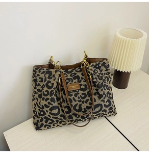 Macro shot of stylish leopard print tote bag with brown leather straps and metal detail