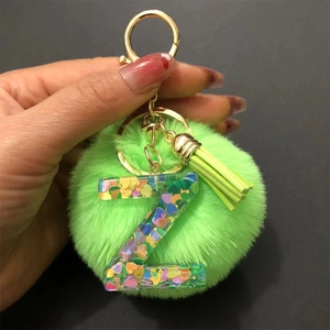 Close-up of green pompom keychain with resin letter Z charm and heart sequins