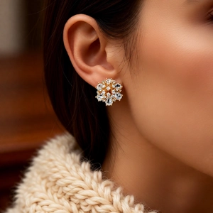 Close-up of 14k gold-plated pearl flower stud earrings worn by a model in soft lighting