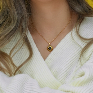 Detail of vintage gold twisted chain necklace featuring a square black gemstone pendant