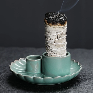 Sage bundle on celadon lotus leaf tray with smoke on dark textured background