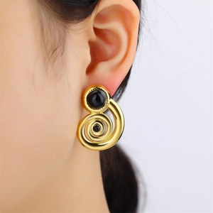 Detailed shot of vintage golden spiral earrings with black round beads worn by a model