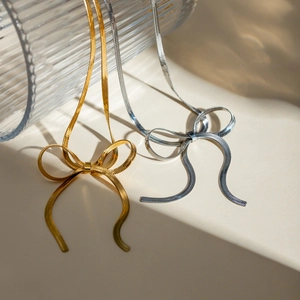 Close-up of gold and silver snake chain necklaces featuring unique 3D bow pendants