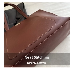 Close-up of neat stitching details on large capacity dark leather tote bag