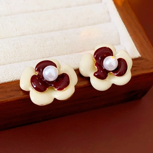 Dettaglio di orecchini vintage a fiore con perle e centri in smalto rosso lucido