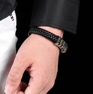 Detail of woven black leather bracelet with gold and silver dual-tone metal clasp
