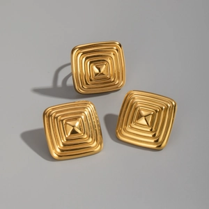 Macro detail of gold square jewelry set with geometric concentric relief patterns
