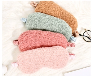 Multi-colored plush teddy fleece sleep masks stacked on soft white faux fur texture
