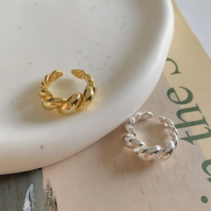 Detail of twisted rope rings in gold and silver finish on a ceramic plate background