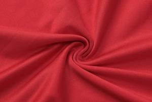 Close-up of red pleated dress fabric showing fine mesh texture and soft material finish