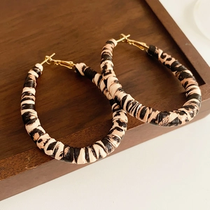 Close-up of leopard print hoop earrings with brown and black leather texture